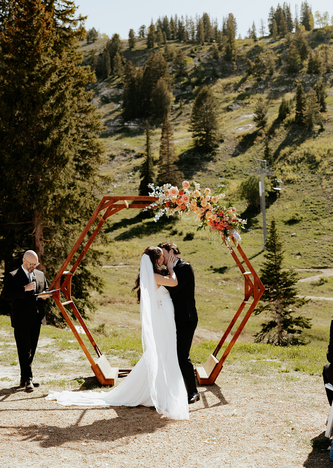 a bride and groom kissing for the first time after their ceremony at a ski resort in utah