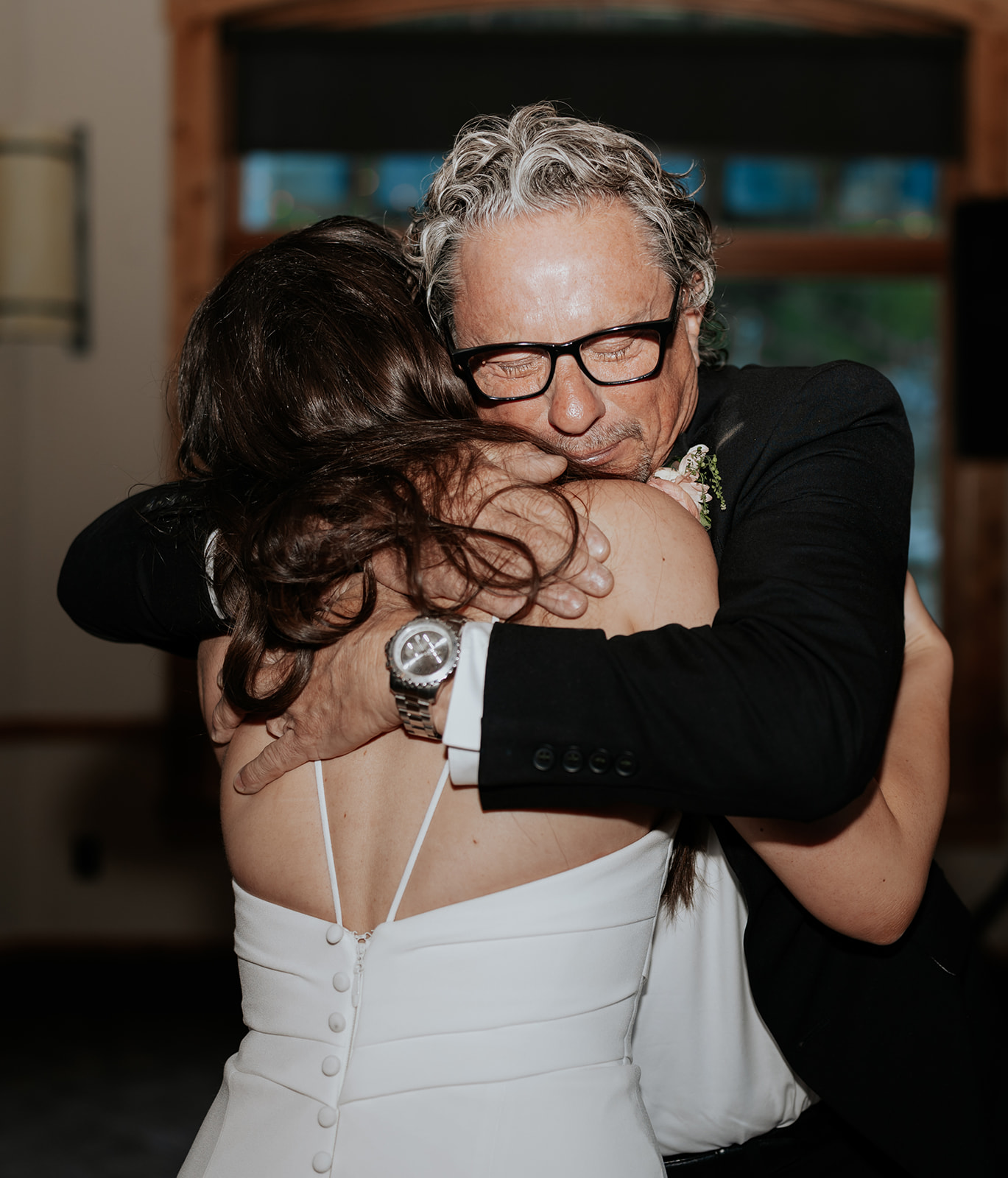 A father hugging his daughter during a father-daughter dance at her wedding at a ski resort.